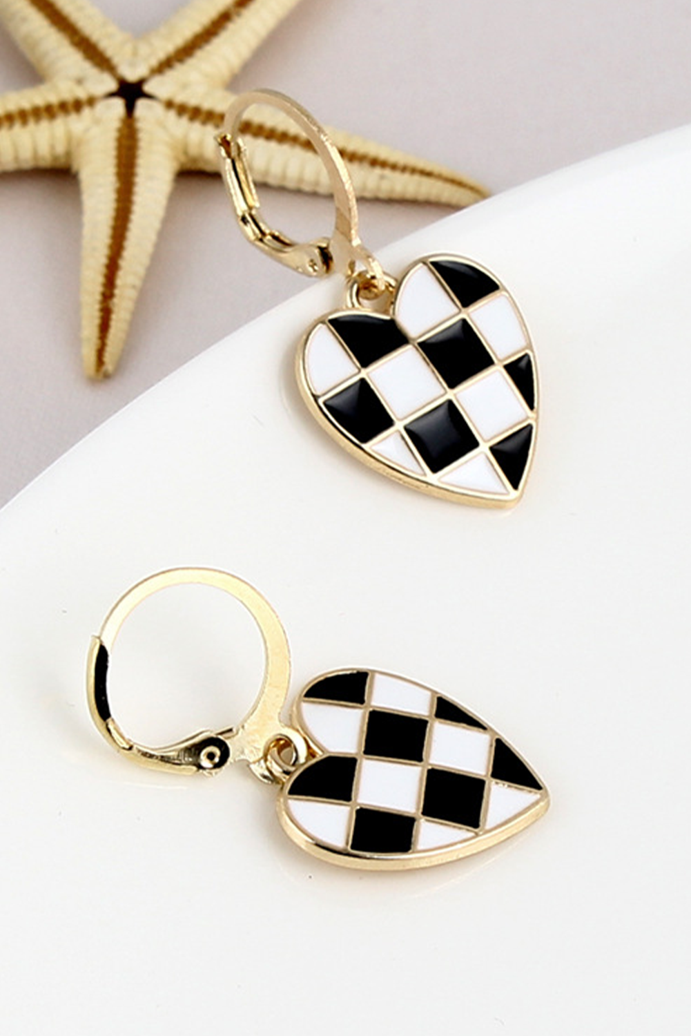 Heart-shaped earrings with black and white checkered design on a light background