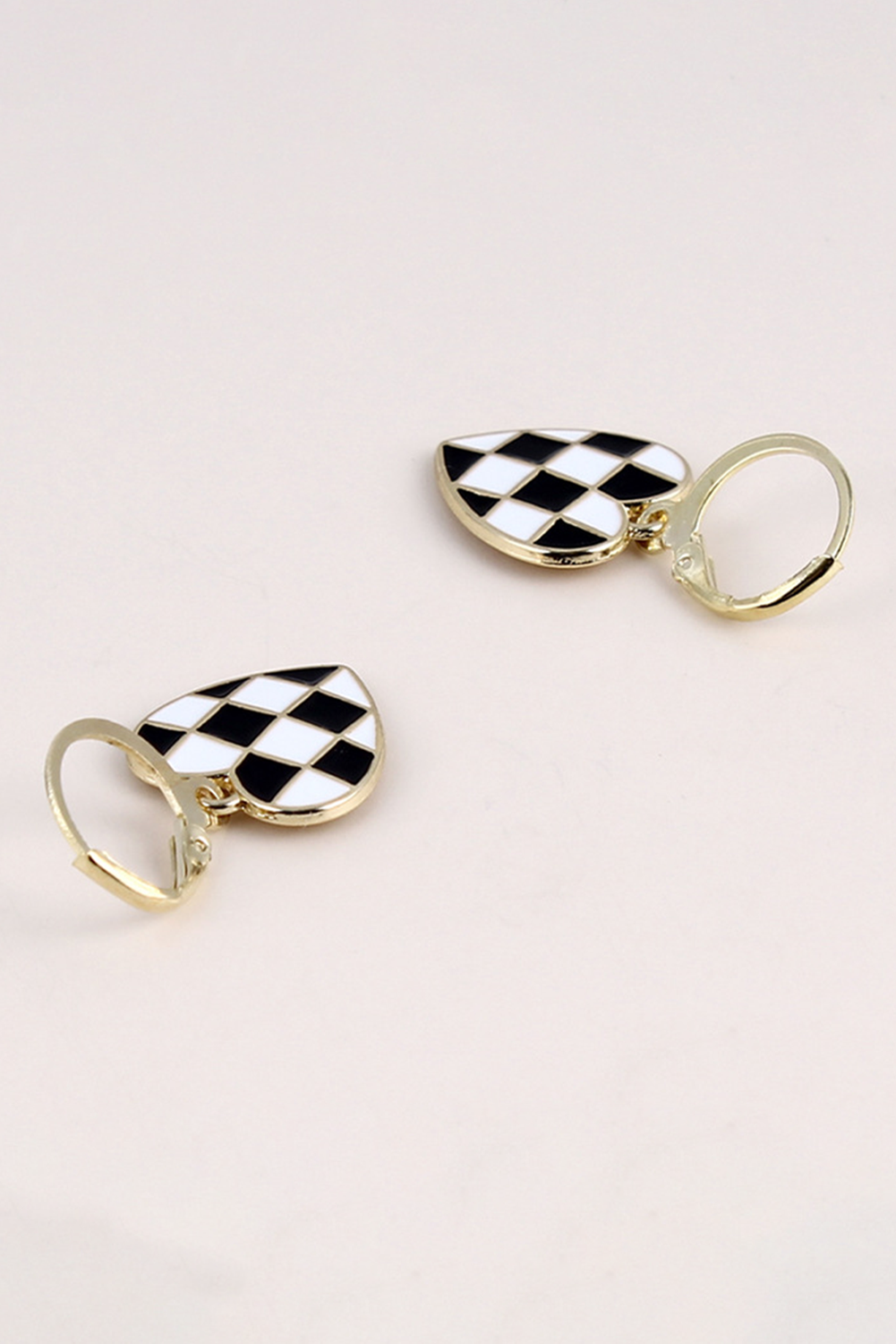 Pair of checkered heart-shaped earrings on a light pink background