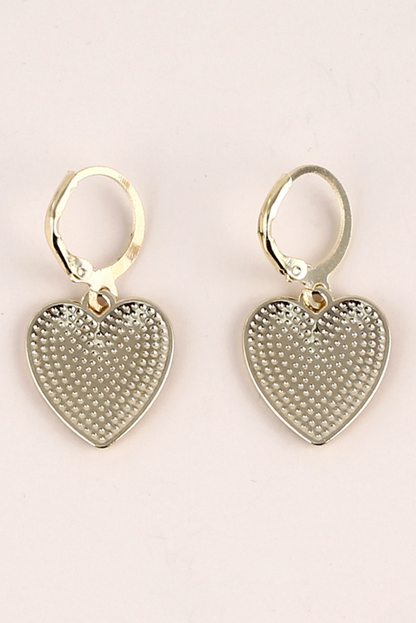 Heart-shaped silver earrings on a light pink background
