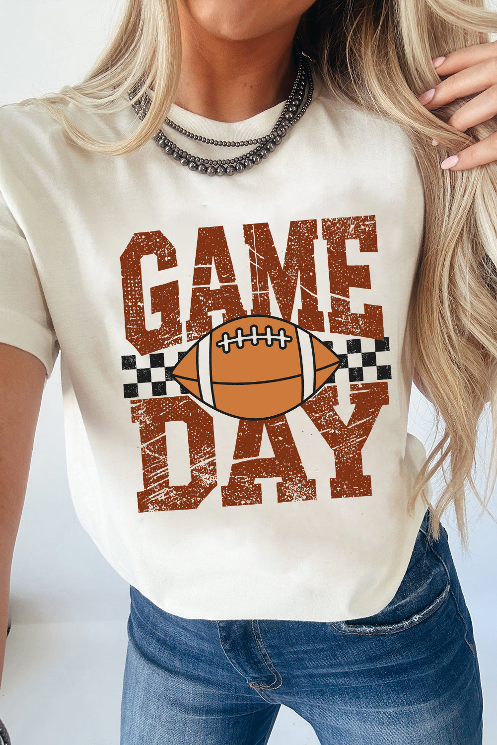 Person wearing a white t-shirt with 'Game Day' and football graphic.