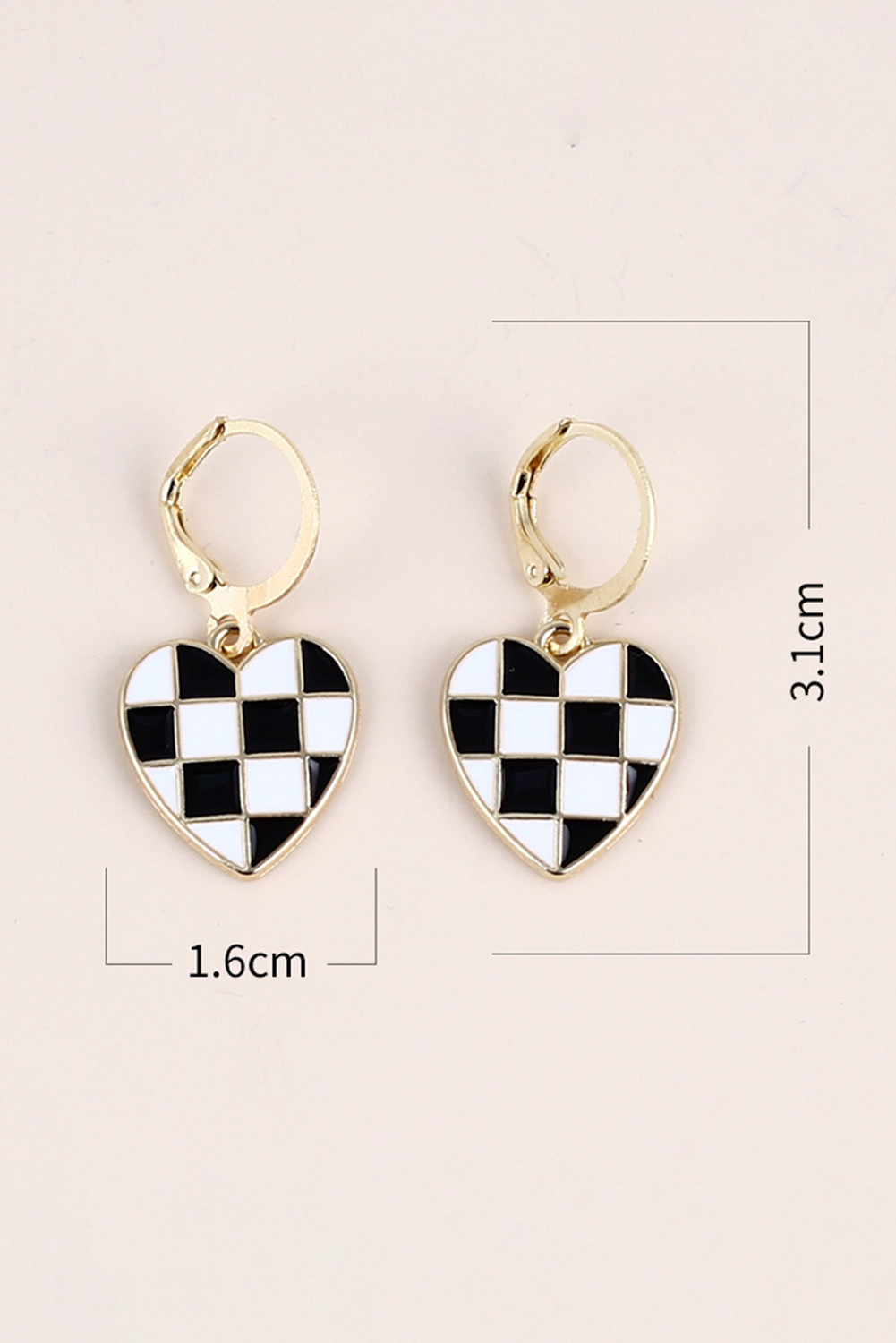 Heart-shaped checkered earrings with gold hooks on a light pink background